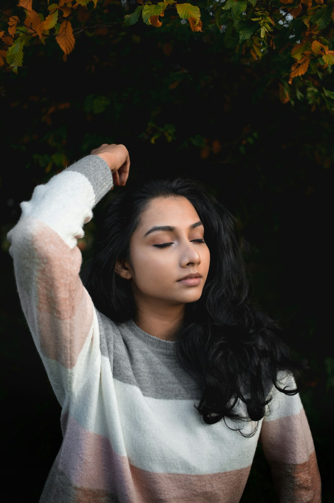 Portrait of a young British Indian woman with long dark hair in a light sweater